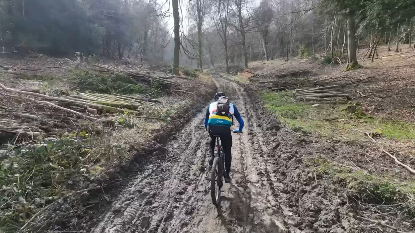 Mountain biker on a muddy woodland track during the M25 bridges ride