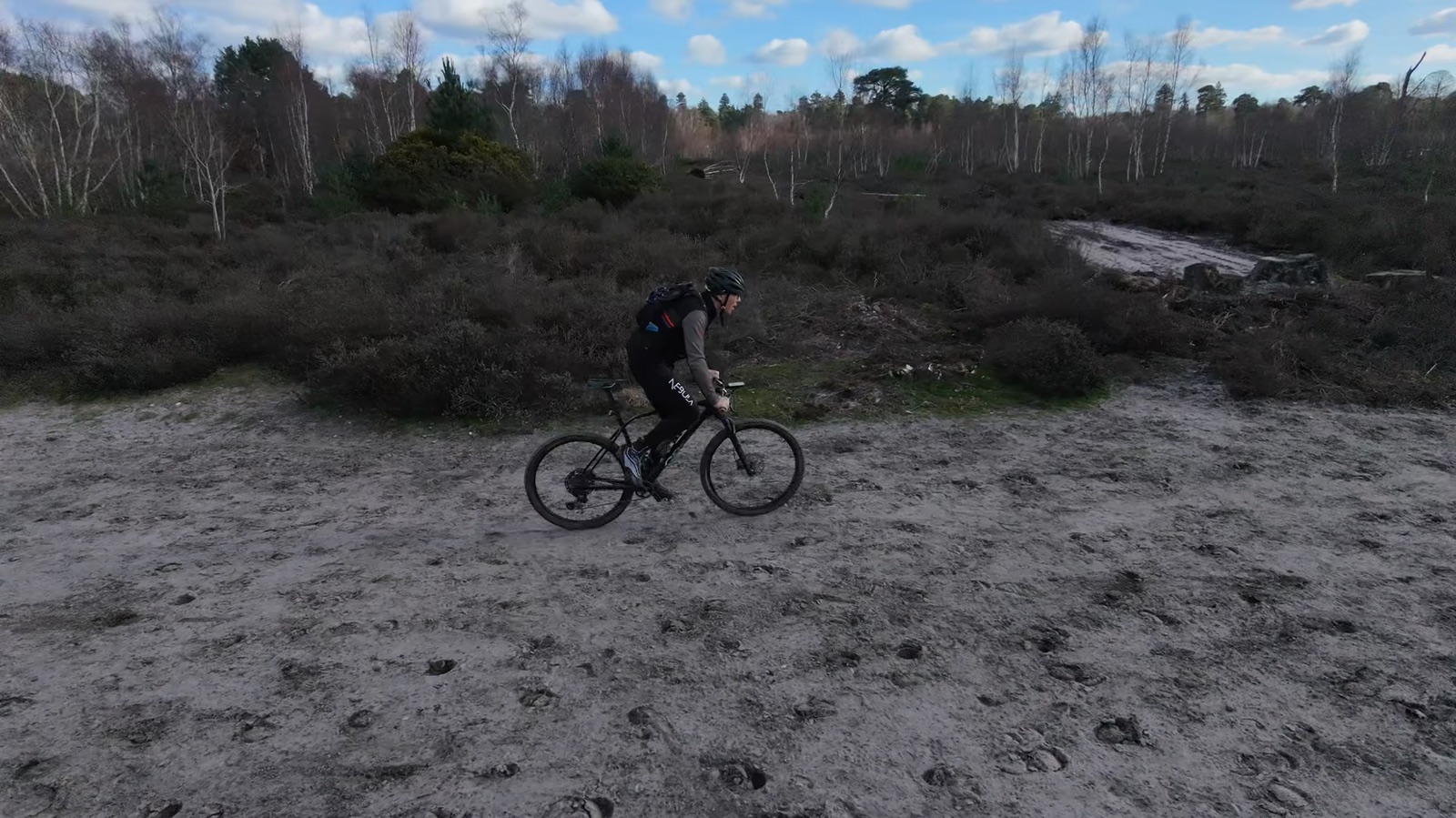 Drone view of a mountain biker crossing sandy ground at Ockham Common
