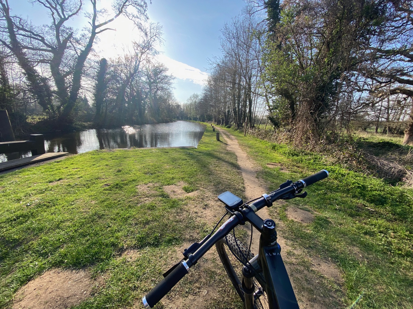 Mountain-bike cockpit beside a waterside trail near Ripley